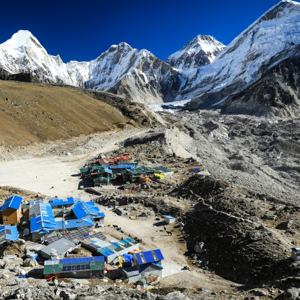 Himalayan mountain village with colorful buildings at the base of snow-capped peaks.