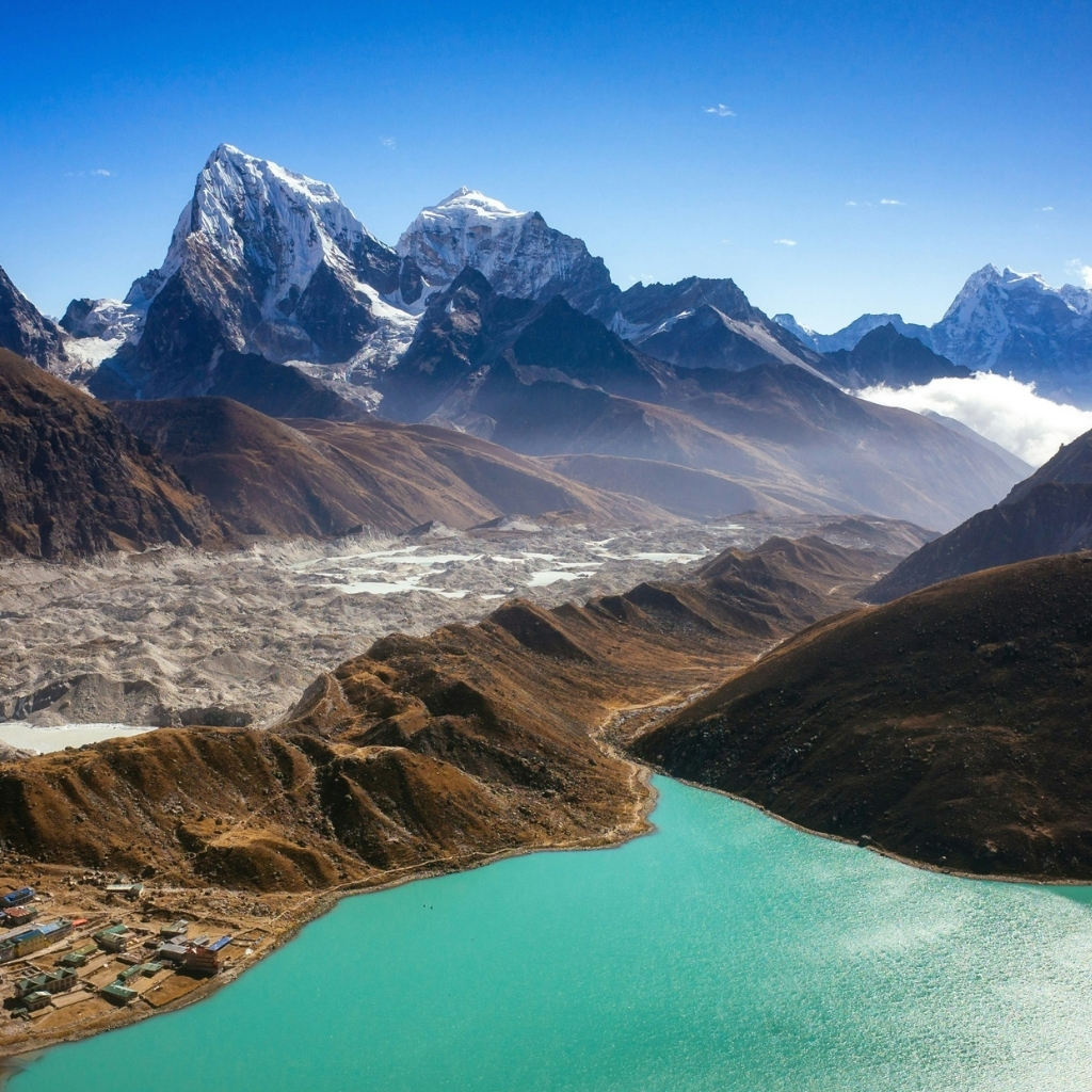 Himalayan mountains with snow-capped peaks and a turquoise glacial lake in the foreground.