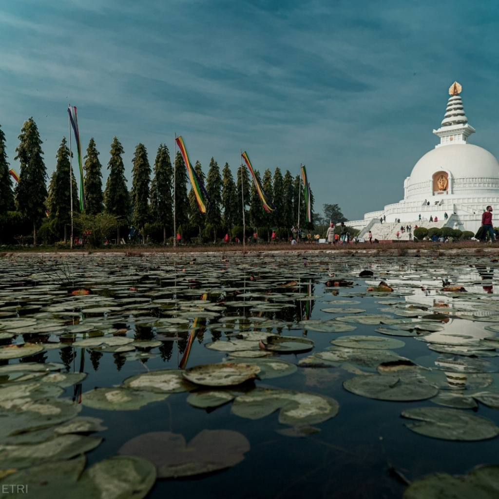 Ancient stupa with lotus pond and colorful prayer flags in Nepal.